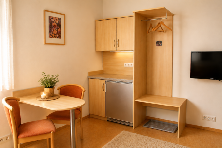Kleine Wohnung mit einem Esstisch, Kühlschrank und Garderobe.