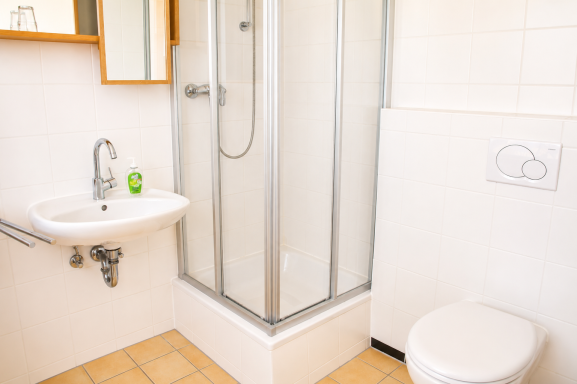 Kleinbad mit Dusche, Waschbecken und Toilette in heller Farbgebung.