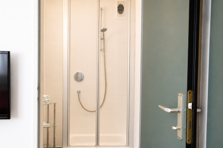 Dusche mit gläserner Kabine und moderner Armatur, Tür offen.