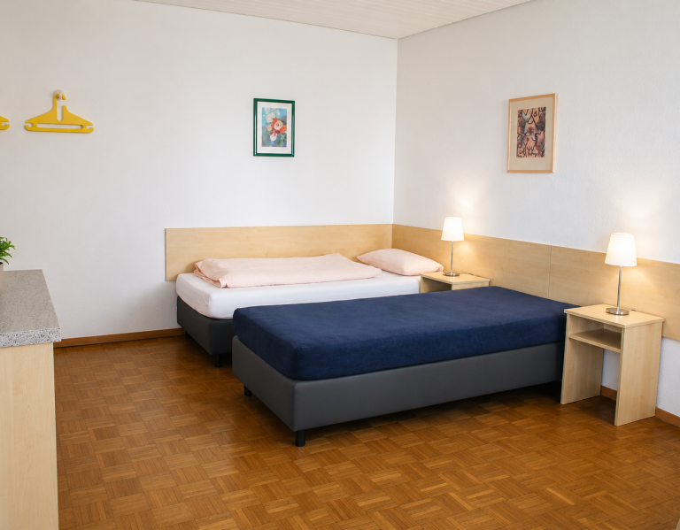 Helles Hotelzimmer mit zwei Betten, Nachttisch und einempflanzen.