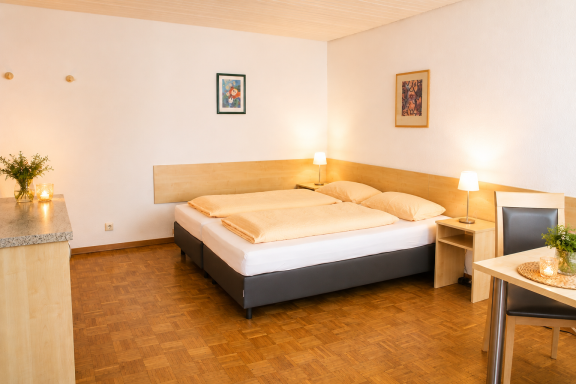 Helles Schlafzimmer mit Doppelbett, Nachttischen und einem kleinen Tisch.
