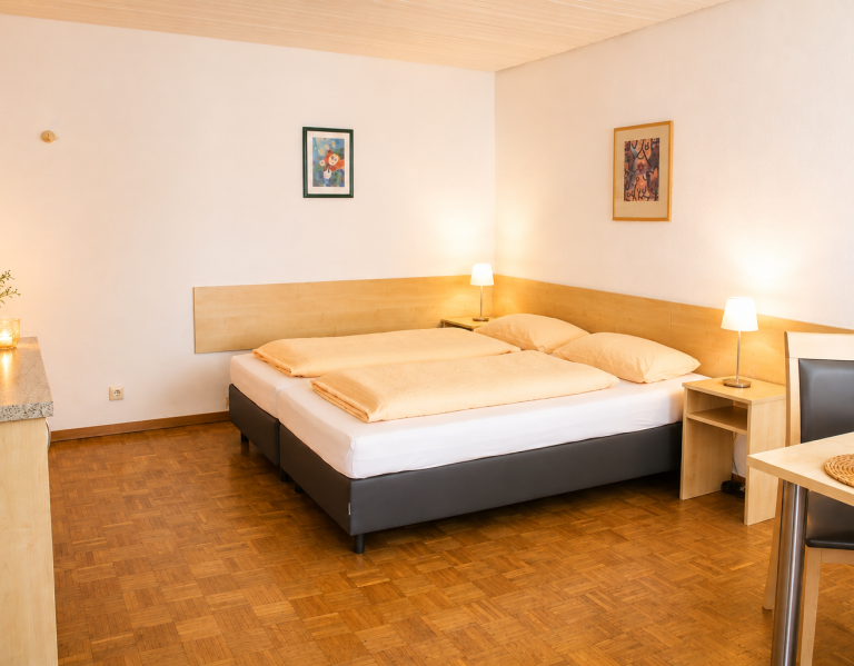 Helles Hotelzimmer mit zwei Betten, Nachttisch und einempflanzen.